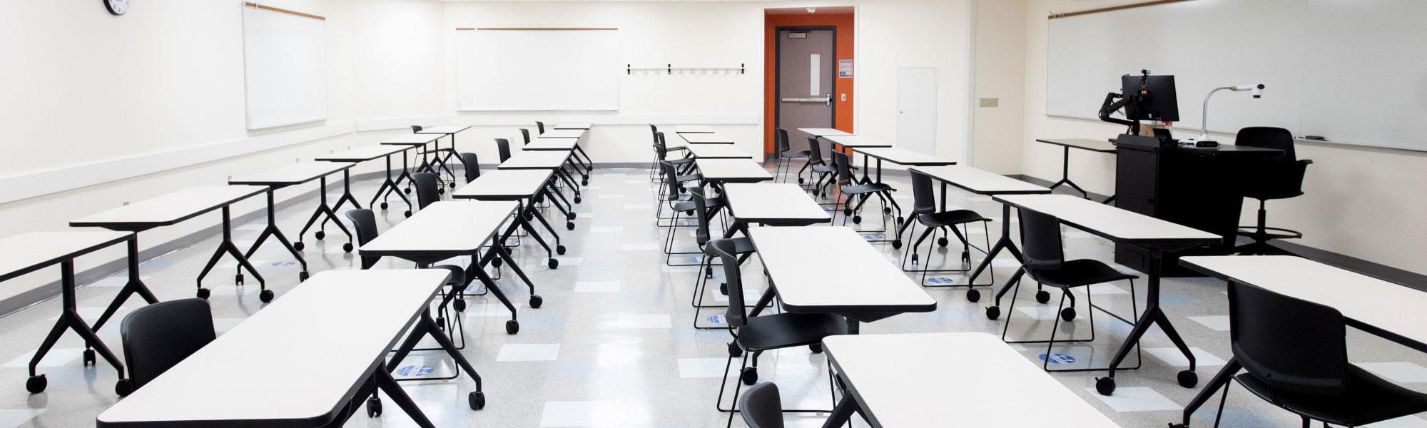 Photograph of a classroom with rows of tables and chairs.